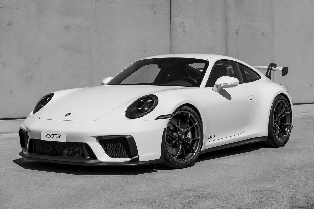 Porsche 911 GT3 sports car in black and white, three-quarter front view with its fixed rear wing